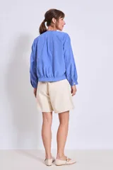 Cazadora color verde oliva con cuello redondo, cierre frontal con botones y mangas largas con puños elásticos.