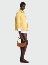 Bolso hobo de cuero color marrón, con cierre de solapa con botón a presión y correa corta para llevar al hombro. Incluye charm colgante con cuentas de madera y piedra.
