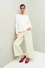 Camisa celeste de corte holgado con botones frontales, canesú con tablas y mangas 3/4 amplias con puño elastizado.