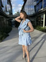 Chaleco blanco de cuero sintético con cierre cruzado, cuello solapa y cinturón con hebilla.