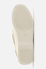 Zapato náutico color crema de cuero, con cordones alrededor del tobillo y suela plana.