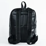Mochila negra de cuero sintético con diseño de hexágonos acolchados. Tiene un compartimento principal con cierre, un bolsillo frontal con cierre y correas ajustables para los hombros.