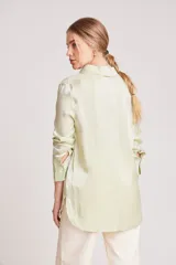 Camisa verde claro de corte recto y mangas largas con puños abotonados. Cierre frontal con botones.