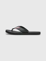 Ojotas negras Tommy Hilfiger con tira ancha de poliuretano acolchada y suela de goma EVA. Detalle de cinta distintiva con los colores de la marca en la tira.