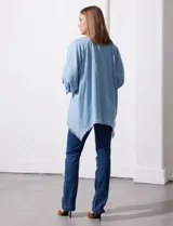 Camisa celeste de tencel, corte amplio, con cuello mao, escote en V y abotonadura frontal. Tiene bolsillos aplicados en el pecho, mangas 3/4 regulables con presilla y ruedo desflecado.