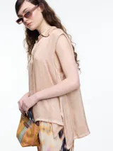 Camisa gris sin mangas confeccionada en viscosa teñida en frío, con efecto gastado. Tiene cuello clásico, cartera oculta y ruedo irregular más largo en los laterales.