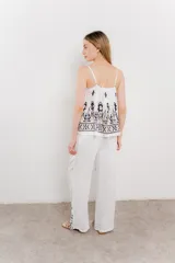 Pantalón blanco con estampado geométrico en azul y marrón, de calce relajado y caída fluida.