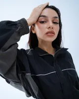 Campera deportiva bomber negra con recortes y vivos blancos.