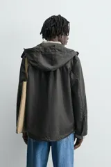 Parka relaxed fit color negro confeccionada en tejido de lino que repele el agua. Tiene cuello con capucha ajustable, mangas largas con puños abotonados, bolsillos frontales con solapa y cierre frontal con cremallera oculta por solapa con botones a presión.