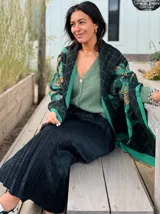 Pashmina estampada con diseño de rombos y hojas en tonos verde, negro y beige.