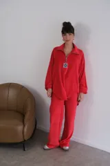 Buzo rojo de plush terciopelo con cierre parcial frontal y detalle de etiqueta con logo en el pecho.