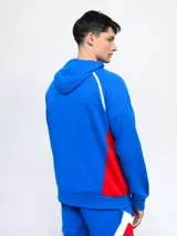 Canguro hoodie azul con capucha, cordones ajustables, bolsillo canguro y detalles en blanco y rojo en los costados y mangas. Incluye el logo de Umbro y el escudo del Club Nacional de Football en el pecho.