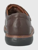 Zapato de cuero negro con ajuste de velcro, forro textil y plantilla de cuero y algodón orgánico. Suela de goma EVA con cortes para mayor flexibilidad.