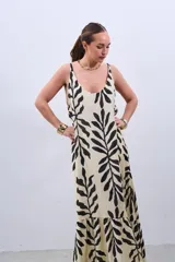 Vestido largo color crudo con estampado de hojas negras, de corte suelto y breteles finos.