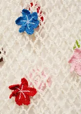 Vestido largo de tejido de punto calado color crudo, con escote en V y mangas largas. Presenta detalles de flores multicolores aplicadas.