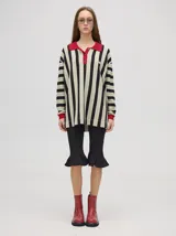 Chomba de corte oversize con cuello camisero, a rayas verticales en color marrón, lila y blanco. Tiene un logo bordado en el pecho y puños en color marrón.
