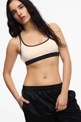 Top deportivo celeste con contorno y tirantes blancos. Presenta copas removibles y el logo de la marca en el contorno inferior.