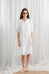 Túnica blanca de lino, corte holgado, con cuello mao, cierre frontal con botones y mangas largas con trabillas para enrollar.