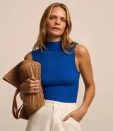 Blusa sin mangas color blanco, con cuello alto y textura acanalada.