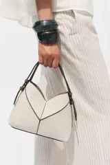 Bolso mini shopper de tejido canvas color crudo con pespuntes en contraste negro. Tiene asas de mano y correa bandolera extraíble. Incluye cartera interior con cremallera dorada.