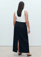 Falda larga negra de lino, con forro de algodón, cintura elástica, tiro medio, diseño lápiz, abertura en la parte posterior y cierre de cremallera lateral.
