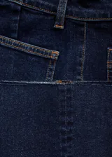 Jeans de tiro medio color azul oscuro, con diseño acampanado, bolsillos de parche delanteros y traseros, y cierre frontal con cremallera y botón.