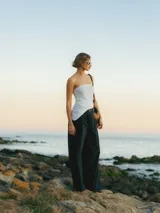 Pantalón negro de pierna ancha con cierre de gancho y cremallera, bolsillos laterales y detalle plisado.