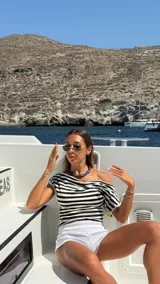 Top negro de manga corta con escote Bardot (hombros descubiertos), confeccionado en encaje floral transparente.