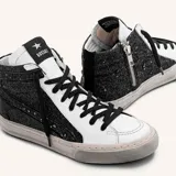 Zapatillas de caña alta de cuero vacuno blanco con glitter negro en los laterales y estrella de cuero negro. El interior es de cuero y la suela de caucho cosida.