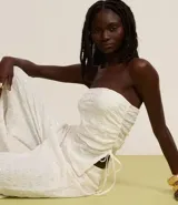 Top sin breteles de lentejuelas color blanco, con escote recto y lazo fruncido en el lateral.