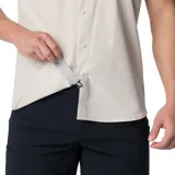 Camisa de manga corta color gris oscuro, con cierre de botones frontal, dos bolsillos en el pecho (uno con cierre de cremallera y otro con velcro), ventilación en la espalda y tecnología Omni-Shade™ Broad Spectrum UPF 50 y Omni-Wick™.