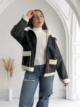 Campera de ecocuero negra con interior de corderito blanco, cierre frontal con cremallera y bolsillos laterales.
