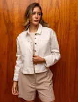 Campera de denim blanca con cuello con solapa, abertura central con botones metálicos y bolsillos delanteros.