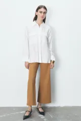 Camisa rosa claro confeccionada en hilatura con modal, de corte holgado, con cuello solapa, manga larga terminada en puño, dos bolsillos con solapa en el delantero y cierre frontal con botones.