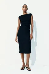 Vestido midi negro de punto arrugado con mangas japonesas y escote barco. Diseño ajustado con laterales fruncidos para un efecto drapeado que realza la figura.
