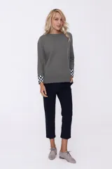 Sweater azul marino de tejido de punto con cuello redondo y puños con diseño a cuadros blancos y negros.