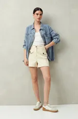Short color crema de tiro alto, con bolsillos delanteros con solapa y botones a la vista.