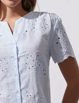 Blusa celeste de algodón con bordado broderie, cuello a la base con abertura central y botones.