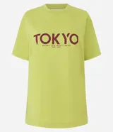 Remera verde claro de algodón con cuello redondo y mangas cortas. Estampado frontal con la palabra "TOKYO" en color borgoña y la frase "Where Zen Meets The Neón" debajo.