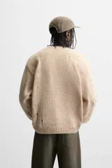 Sweater color beige con detalles de roturas y agujeros.
