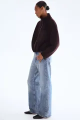 Campera corta de tejido efecto neopreno color marrón oscuro o ciruela, con cuello chimenea alto y cierre frontal metálico. Presenta hombros caídos y un bajo fruncido con elástico que le da un calce holgado.