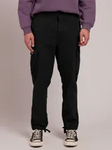 Pantalón cargo color caqui, de corte recto, con bolsillos laterales y traseros. Se ajusta a la cintura con cinturón de cuero marrón.