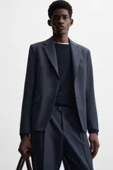 Blazer azul marino de corte recto confeccionado en tejido con lana. Tiene cuello con solapas de muesca, manga larga con puños abotonados, bolsillo de vivo en el pecho, bolsillos de solapa en la cadera, bolsillo interior y cierre frontal con botones.