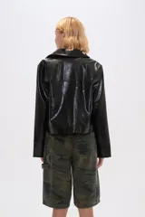 Chaqueta corta marrón de cuero sintético con cuello camisero, cierre frontal con botones metálicos y bolsillos tipo parche con botón.