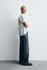 Pantalón de jeans de algodón, corte baggy fit, tiro medio, con efecto lavado en tonos grises y verdes. Presenta cinco bolsillos y cierre frontal con cremallera y botón.