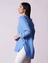 Túnica celeste de algodón con escote en V y detalle de puntilla. Tiene mangas largas con puños abotonados y cierre frontal con botones.