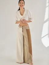 Pantalón ancho de denim con diseño patchwork en diferentes tonos de azul, con tiro alto, corte holgado y cierre frontal con botones.