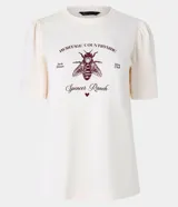 Blusa slim de algodón color crema, con cuello redondo y mangas cortas abullonadas. Presenta un estampado con lettering en inglés y una ilustración de una abeja.