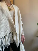 Ruana color crema tejida en lana merino con flecos.