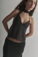 Top halter negro con lunares blancos, de tela tipo gasa, con espalda descubierta y lazos para atar al cuello y la espalda.